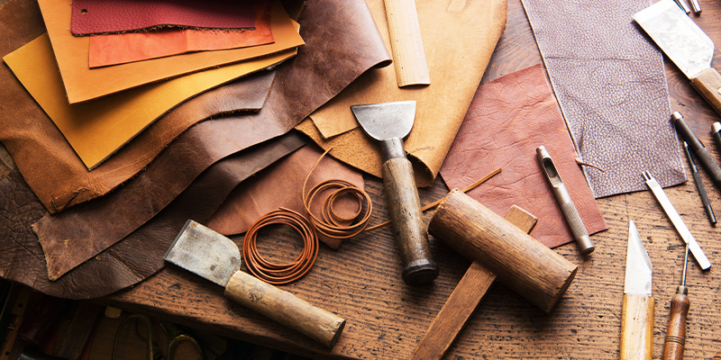 Leather craft or leather working. Selected pieces of beautifully colored or tanned leather on leather craftman's work desk .
